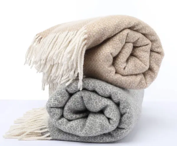 Beyaz arkaplanda iki katlanmış yün battaniye.