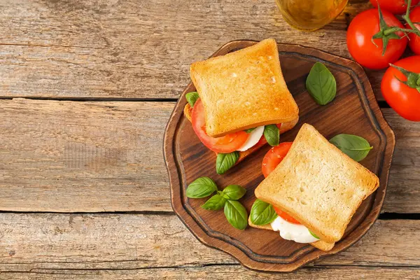 Peynirli, domatesli, ahşap masadaki fesleğenli lezzetli sandviçler. Metin için boşluk