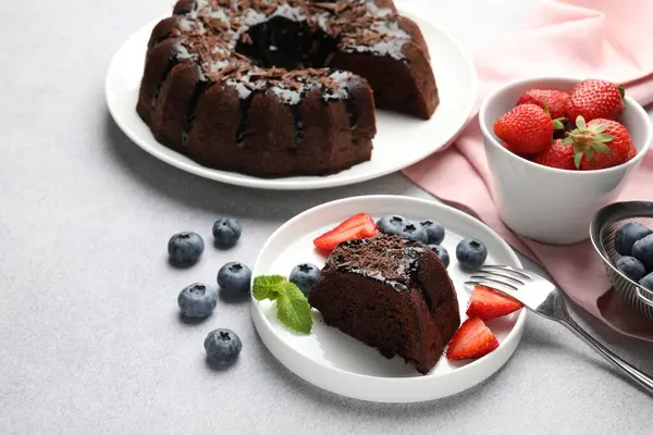 Açık gri desenli masada çilekli ve yaban mersinli lezzetli çikolatalı kek, yakın plan.