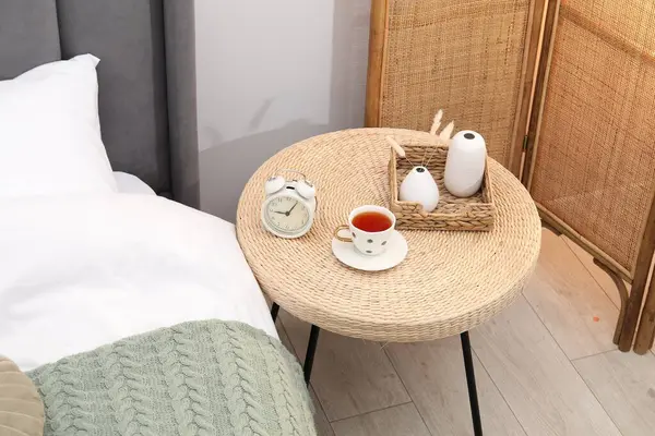 Çalar saati olan yan masa, yatağın yanında bir fincan çay ve dekor, manzaranın üstünde.