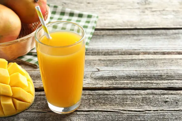 Bardakta lezzetli mango suyu ve ahşap masada taze meyveler, yakın plan. Metin için boşluk