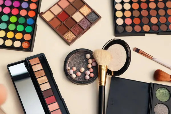 Makyaj malzemeleri ve fırçalar tuvalet masasında, düz yerde.