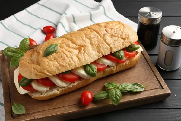 Mozarella peynirli, domatesli, fesleğenli, siyah ahşap masa, yakın plan.