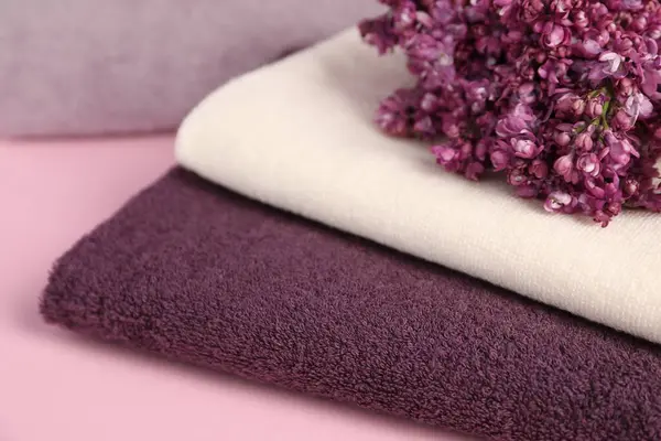 Yumuşak havlular ve pembe arka planda leylak çiçekleri, yakın plan.