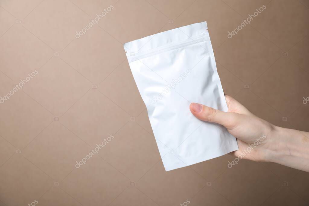 Woman with zipper stand-up pouch on beige background, closeup. Mockup for design