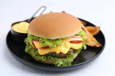 Sos ve patates dilimli leziz bir çizburger, yakın plan.