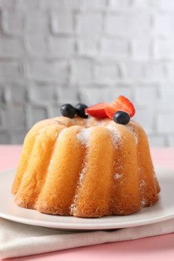 Pembe ahşap masada pudra şekeri ve böğürtlenli Lezzetli kek, yakın plan.