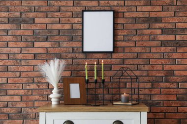 Mum ve tuğla duvarın yanındaki masada yanan mumlar.