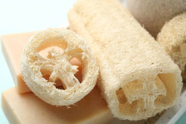 Açık mavi arkaplanda doğal lif süngeri ve sabun, yakın plan.