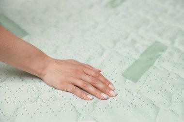 Yatakta yumuşak yatağa dokunan kadın, yakın plan.