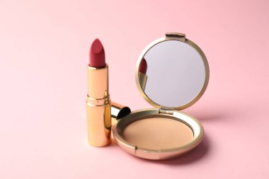 Aynalı açık yüz pudrası ve pembe arka planda ruj, yakın plan.