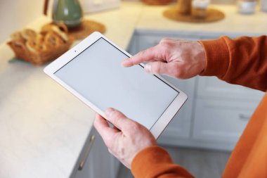 Evinde modern tablet kullanan bir adam, yakın çekim.
