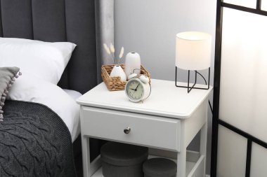 İçinde lamba, çalar saat ve yatağın yanındaki dekorun bulunduğu komodin.