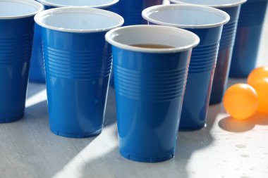 Plastik bardaklar, alkollü içecekler ve açık ahşap masada toplar, yakın plan. Bira pong oyunu