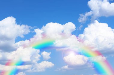Mavi gökyüzünde parlak gökkuşağı güneşli bir günde bulutlarla