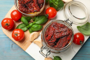 Lezzetli, kurutulmuş domatesler, taze sebzeler, fesleğen ve sarımsak mavi ahşap masa, üst manzara