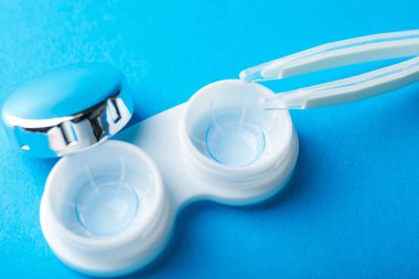 Mavi arkaplanda kontakt lensler ve cımbızlar, üst görünümde