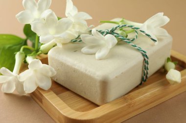 Açık kahverengi arka planda sabun ve yasemin çiçekleri, yakın plan.