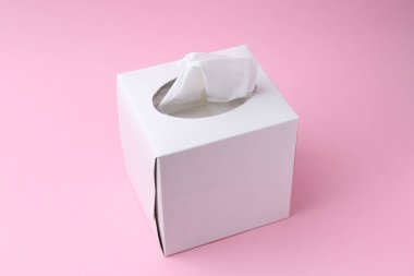 Pembe arka planda kağıt mendilli bir kutu.