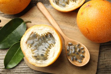 Olgun çarkıfelek meyveleri, tohumlar ve yeşil yapraklar ahşap masada, düz yatıyordu.