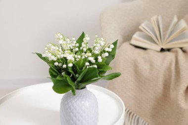 Bir buket güzel vadi zambağı vazoda, kahve masasının üstünde.