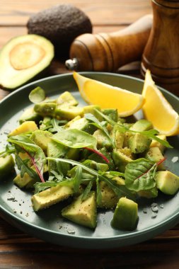 Lezzetli avokado roka, limon ve ahşap masaya sos, yakın plan.