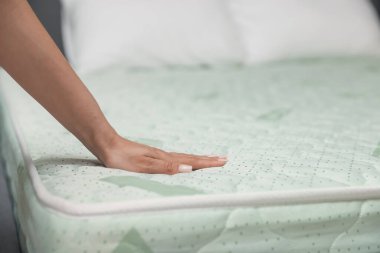 Yatakta yumuşak yatağa dokunan bir kadın, yakın plan. Metin için boşluk