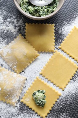 Süzme peynirli ravioli ve ahşap masada ıspanak yapmak.