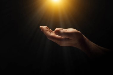 Kutsal ışıkla aydınlatılan adam karanlıkta dua ediyor, yaklaş.