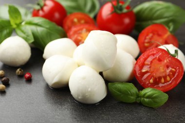 Mozzarella peyniri, domates, fesleğen ve biberler gri masada, yakın plan.