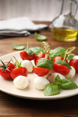 Ahşap masada mozarella, domates ve fesleğen ile aperatifler, yakın plan.