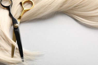 Sarı saç tokası ve makas açık gri arka planda, yakın plan.