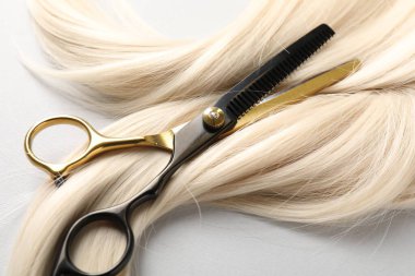 Sarı saç tokası ve makas açık gri arka planda, yakın plan.