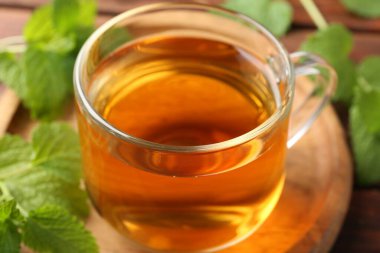 Cam bardakta Aromatik limon merhemi çayı ve masada taze yapraklar, yakın plan.
