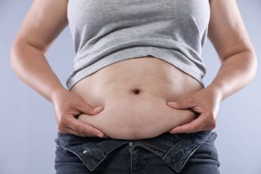 Hafif arka planda aşırı göbek yağı olan kadın, yakın plan. Aşırı kilolu