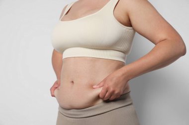 Hafif arka planda aşırı göbek yağı olan kadın, yakın plan. Aşırı kilolu