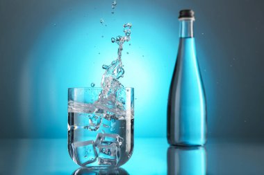 Ayna masasının üzerindeki camdan akan tatlı su, açık mavi gradyan plana karşı. Arka ışıklandırma