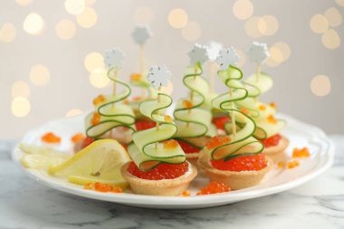 Arka planı bulanık ışıklarla kaplı beyaz mermer masa üzerinde lezzetli kanepeler, yakın plan. Bokeh etkisi