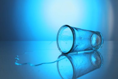 Ters çevrilmiş cam ve dökülmüş su mavi gradyan arkaplan, metin için alan. Arka ışıklandırma