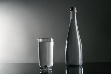 Taze su cam içinde ve ayna masasında gri arka planda.