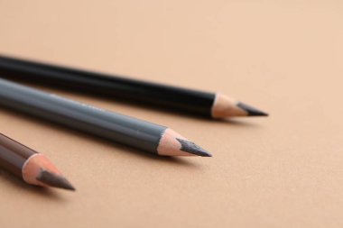 Bej arka planda üç farklı kaş kalemi, yakın plan.