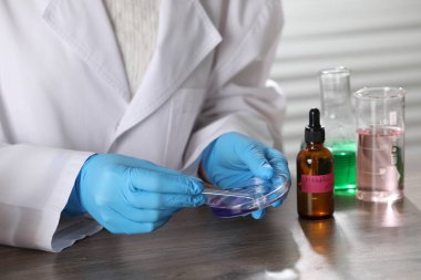 Laboratuardaki ahşap masada lüks parfüm üreten profesyonel parfümcü.