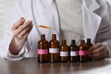 Laboratuardaki ahşap masada lüks parfüm üreten profesyonel parfümcü.