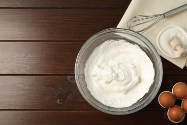 Krem şantili kase, çırpılmış çırpma ve ahşap masada malzemeler, düz yatak. Metin için boşluk