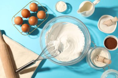 Açık mavi masada çırpılmış krema, yumurta ve diğer ürünlerle çırpın.
