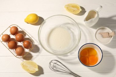 Beyaz ahşap masa üzerinde çırpı çırpı, yumurta beyazı, yumurta beyazı ve diğer ürünler.