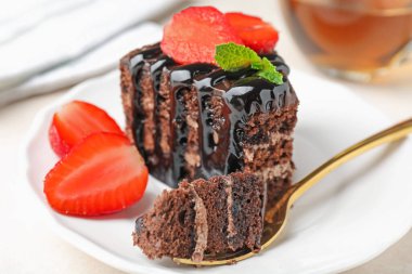 Çilek ve kaşıkla servis edilen bir parça çikolatalı pasta, yakın plan.