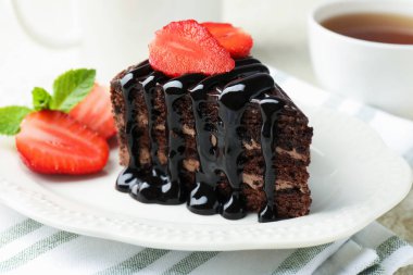 Çilek ve çayla servis edilen bir parça çikolatalı kek, yakın plan.