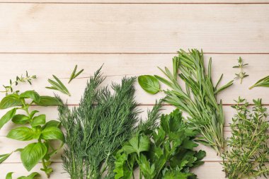 Beyaz ahşap masa üzerinde farklı taze otlar, düz yatış. Metin için boşluk