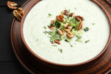 Siyah ahşap masada dereotlu ve cevizli lezzetli salatalık çorbası, yakın plan.